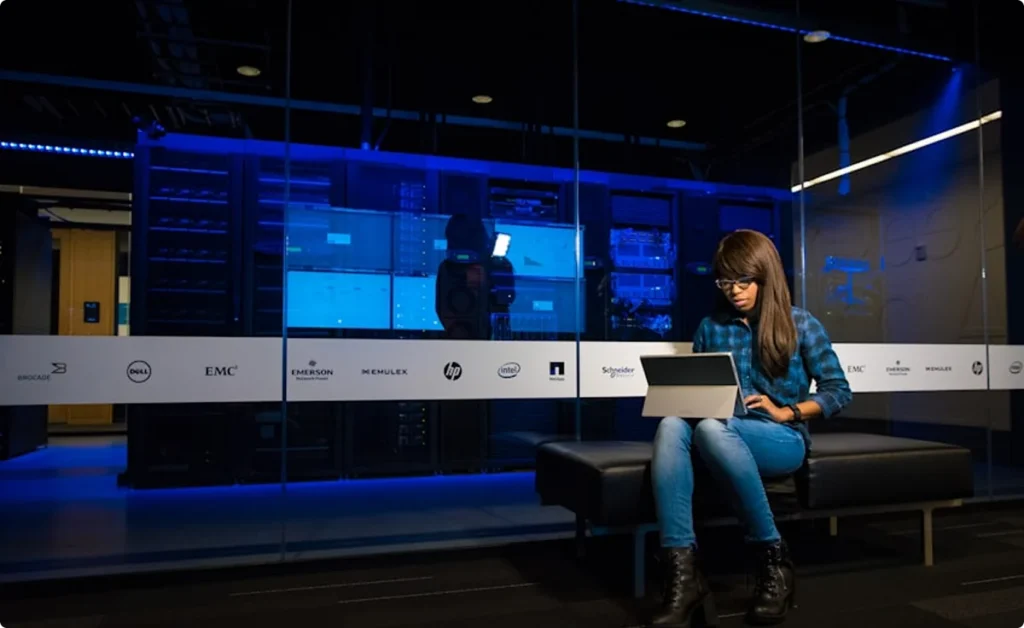 A technician reviews monitoring screens in a blue-lit technology operations center.