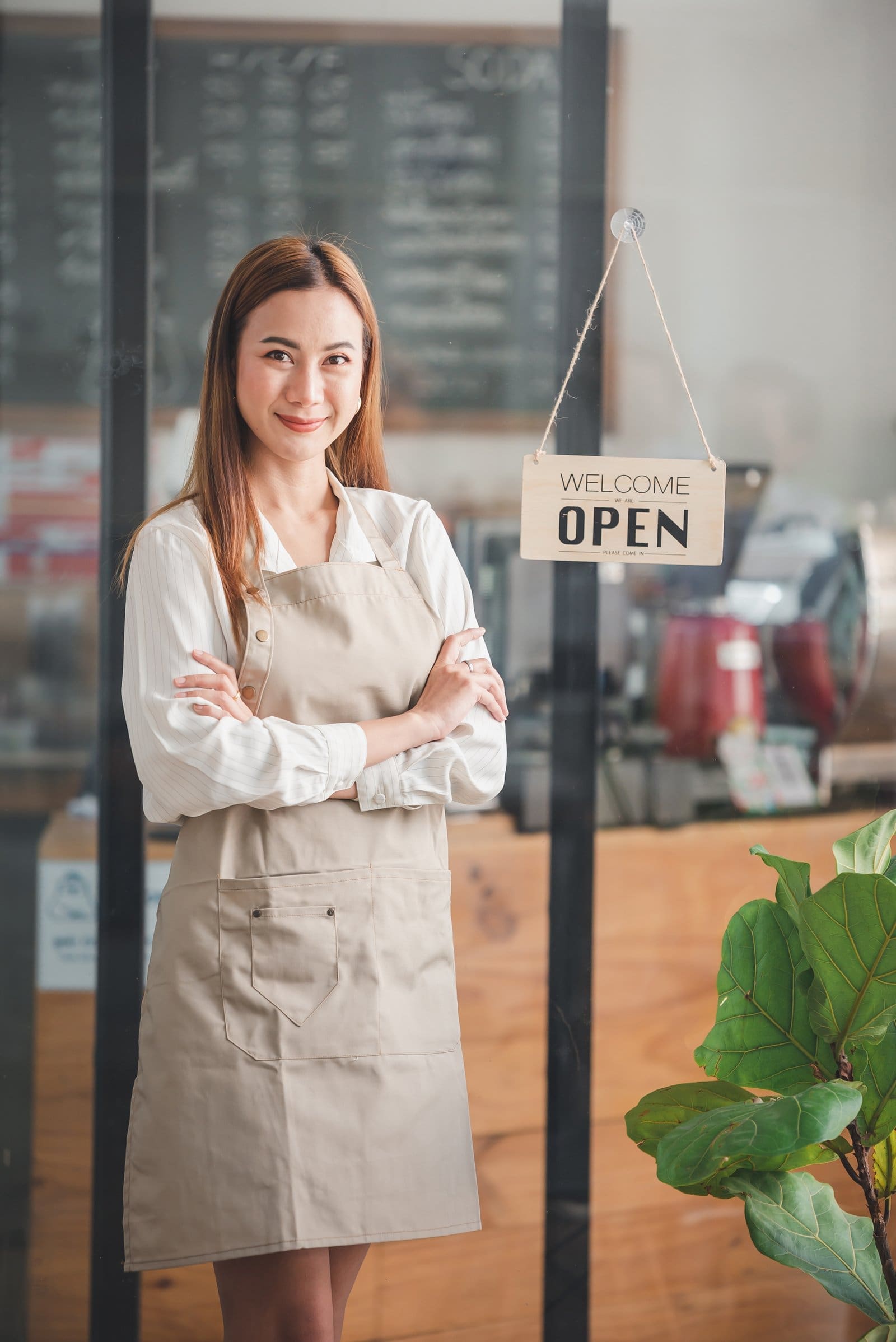 Cafe owner standing beside an open sign at the entrance