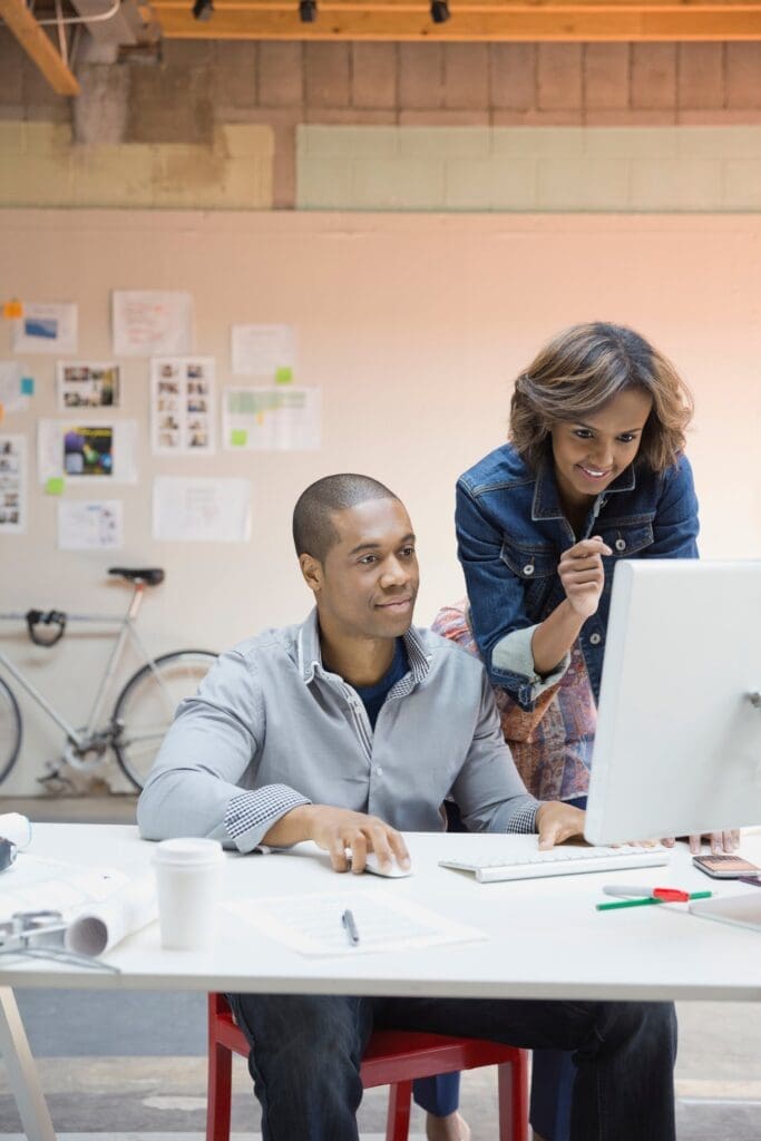 Two colleagues reviewing work together at a computer