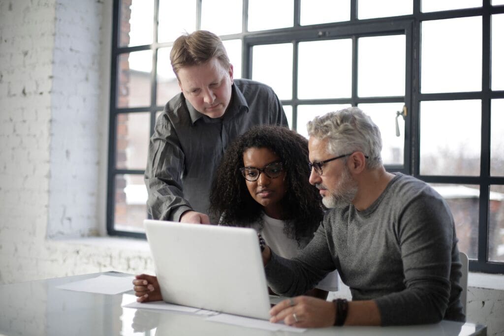 Three colleagues reviewing a project together on a laptop.