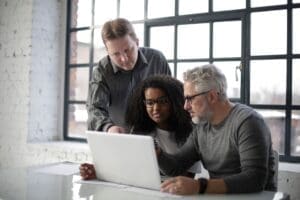 Three colleagues reviewing a project together on a laptop.