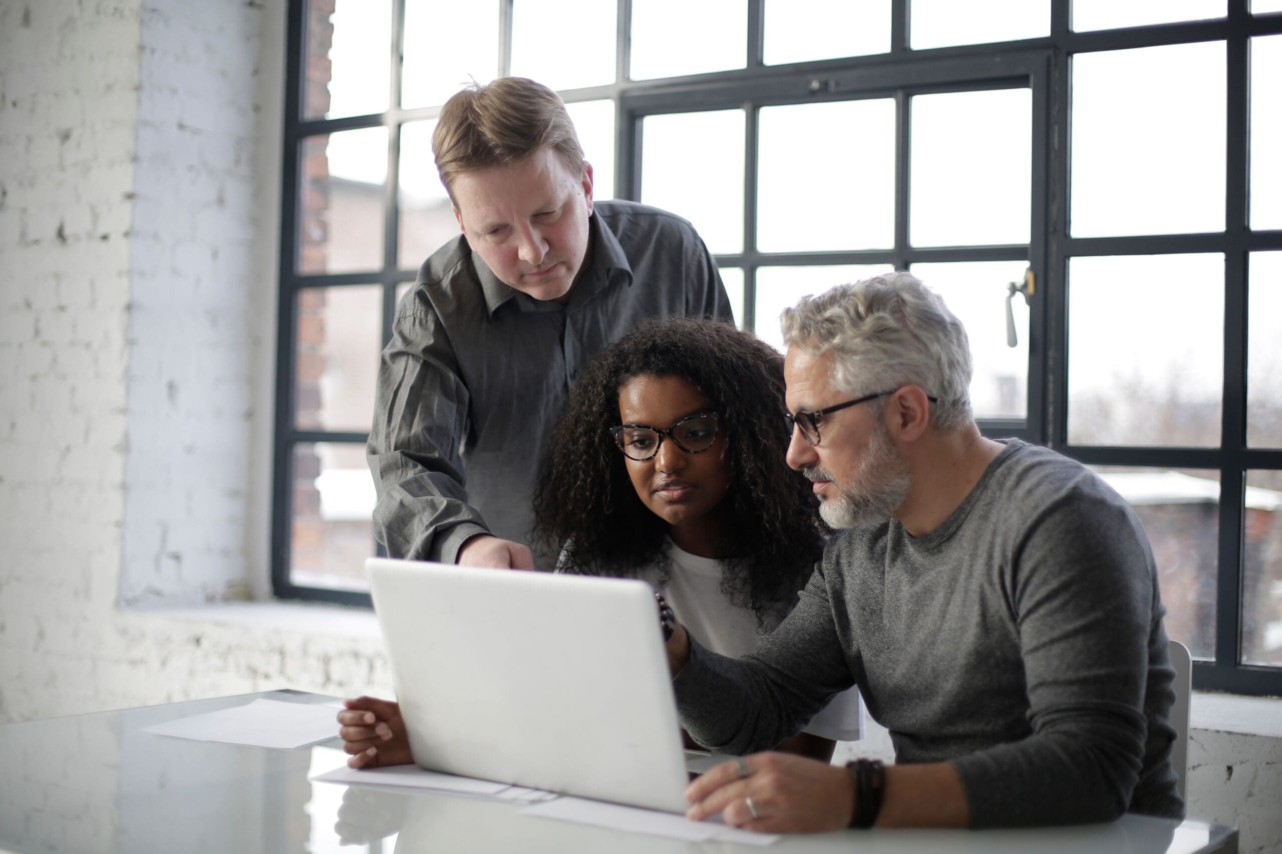Three colleagues reviewing a project together on a laptop.